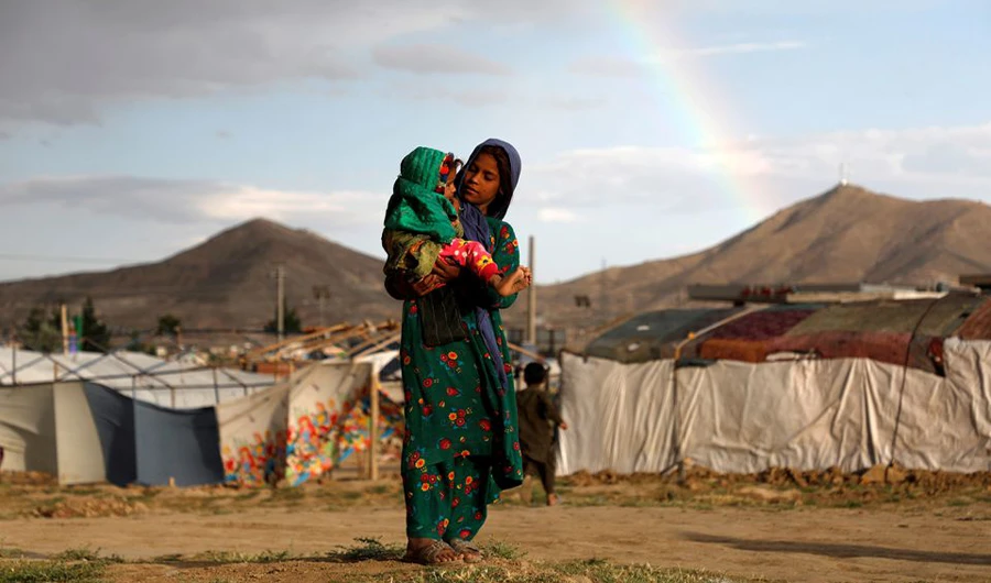 An internally displaced Afghan girl carries a child near their shelter at a camp on the outskirts of Kabul, Afghanistan June 20, 2019. (REUTERS)