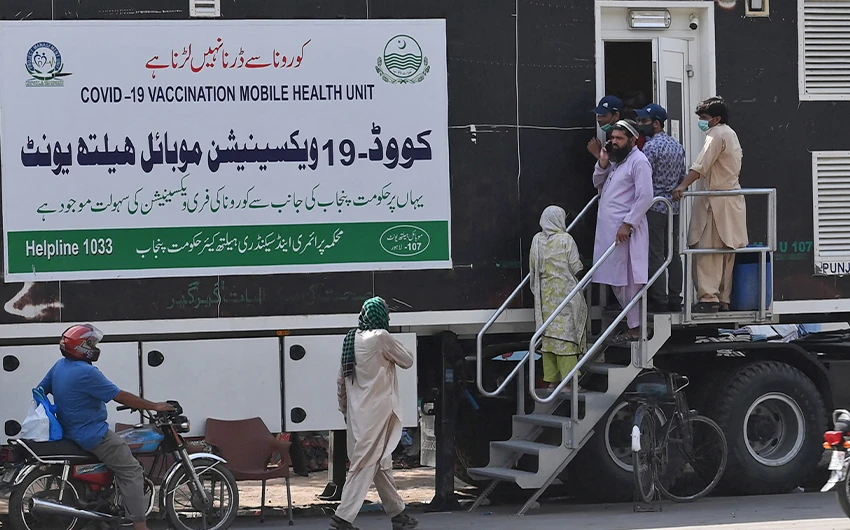People wait for their turn to get a dose of a vaccine against the coronavirus outside a mobile vaccination health unit in Lahore, Pakistan, on July 7, 2021. (AFP)