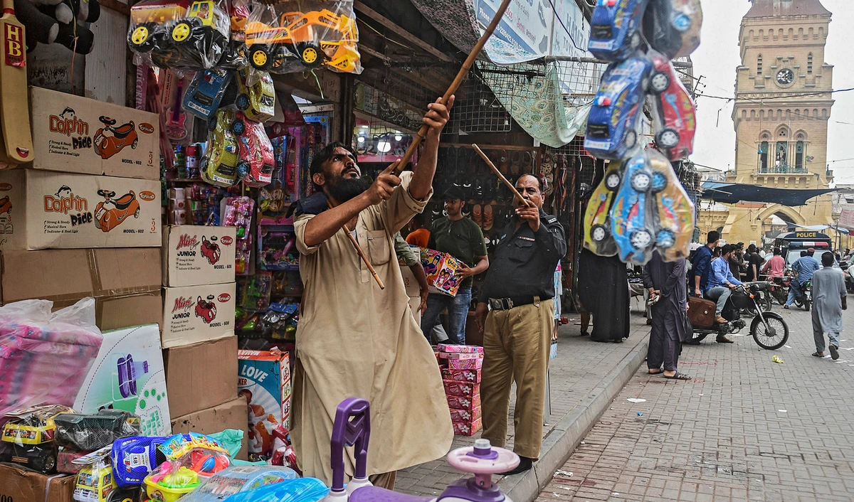 A policeman orders shopkeepers to close their shops after authorities imposed evening lockdowns amidst rising Covid-19 coronavirus cases in Karachi on July 26, 2021. (AFP)