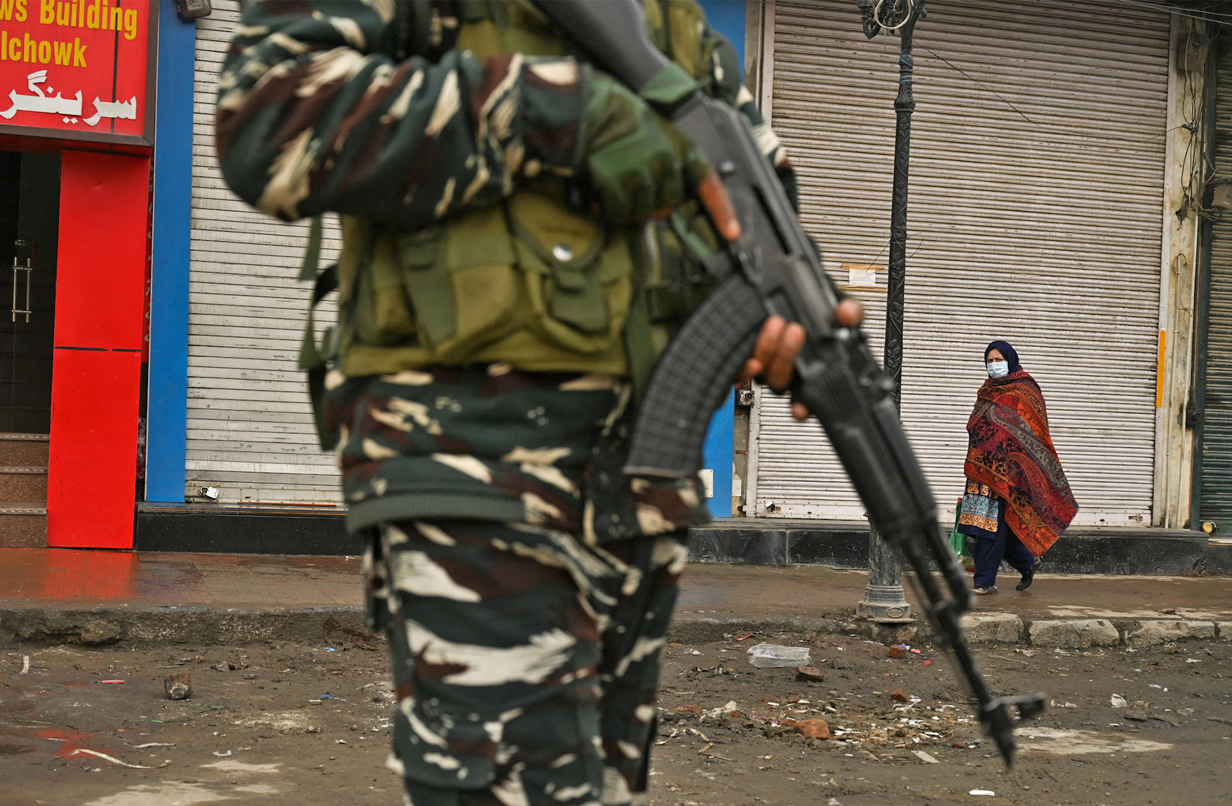 A woman walks past closed shops and an Indian government soldier standing guard during a one-day strike in Srinagar on February 9, 2021. (AFP/File)