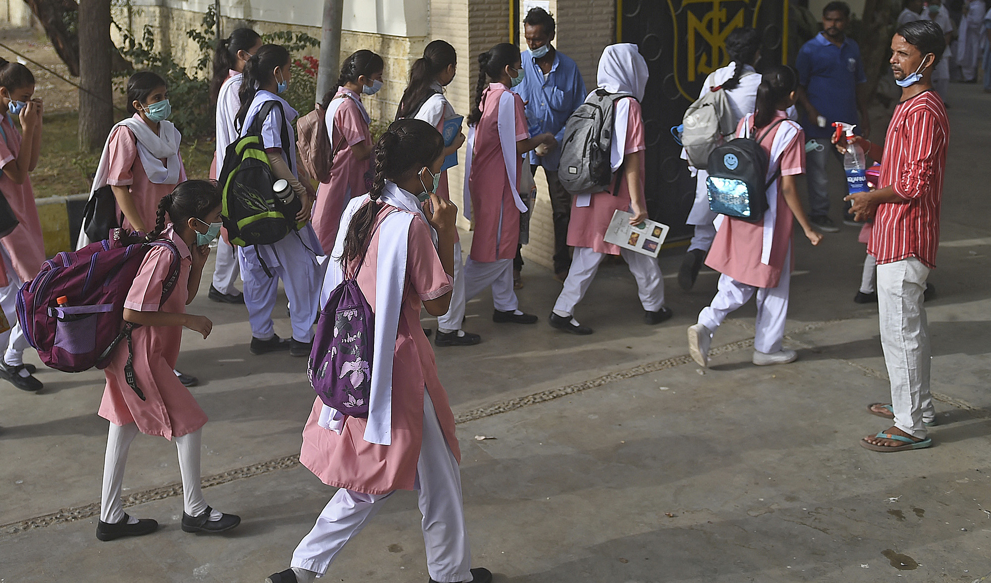 A staff member helps the school children sanitize their hands before entering the premises of a school in Karachi on June 21, 2021. (AFP/File)