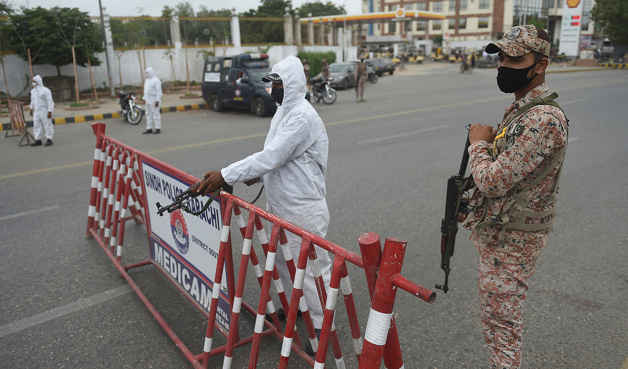 Policemen wearing personal protective equipment (PPE) stand at a security check point on a street in Karachi on August 2, 2021. (AFP)