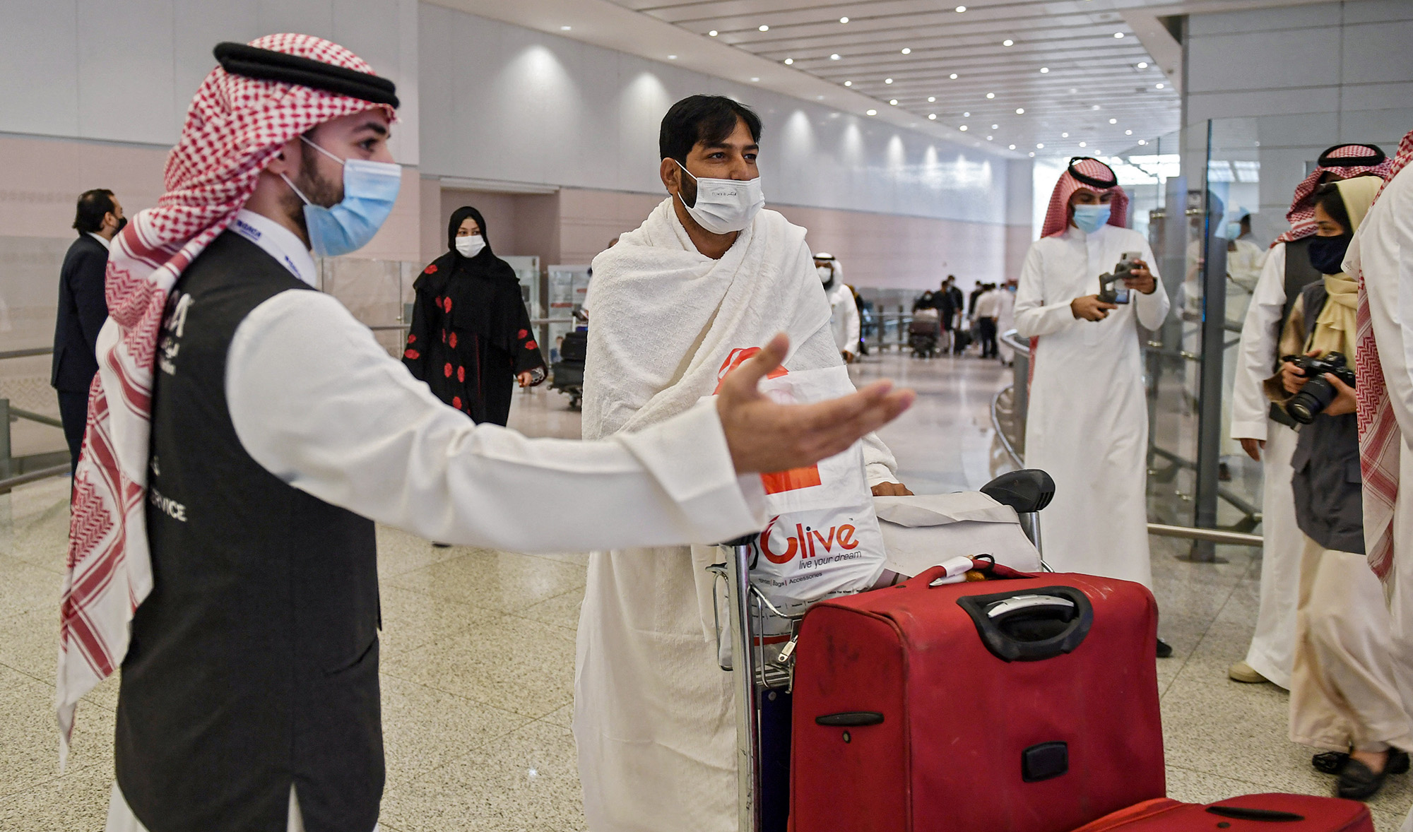 A mask-clad Pakistani traveller arriving to Saudi Arabia to perform the year-round Umrah pilgrimage, is welcomed at King Abdulaziz International Airport in Jeddah on November 30, 2020 (AFP/File)