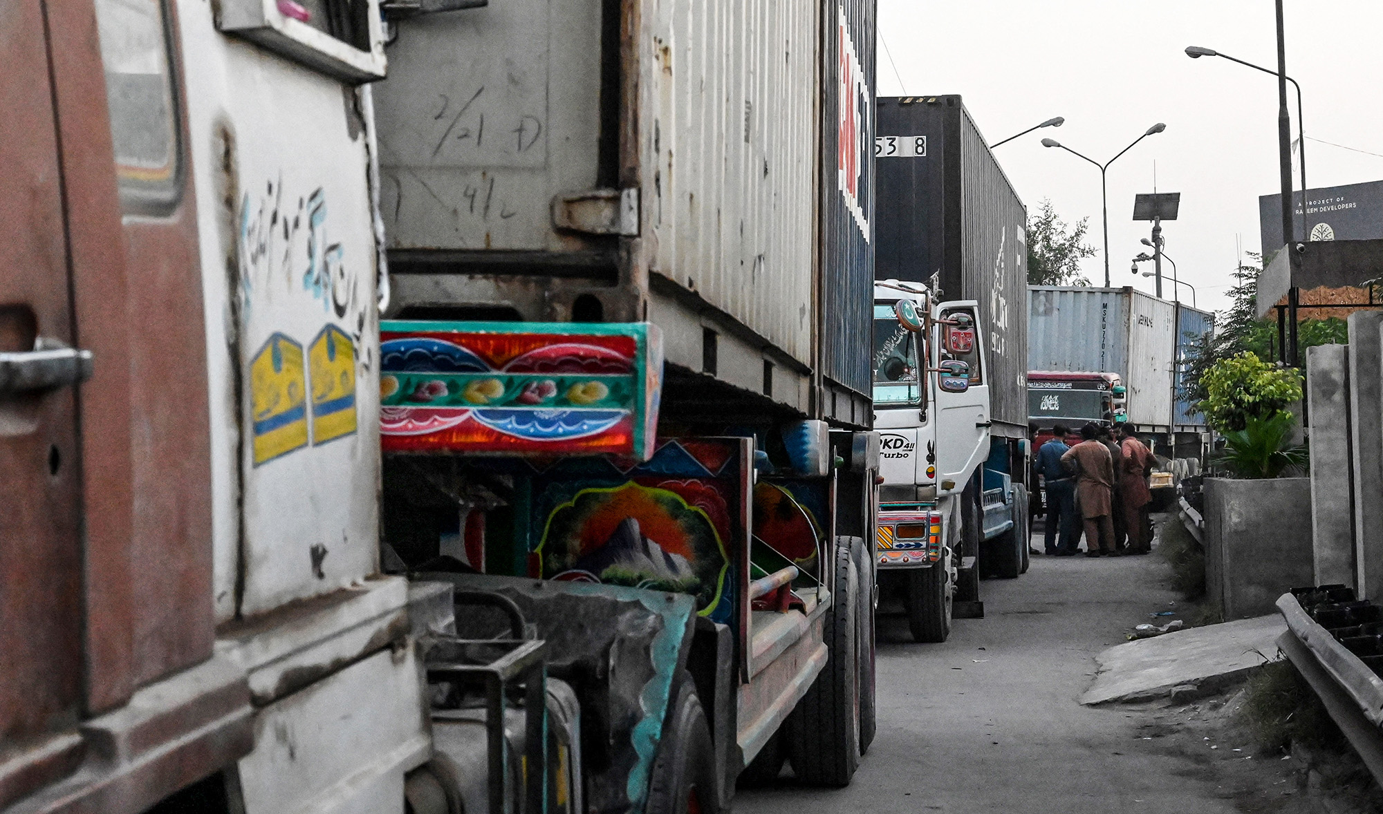 Truck drivers gather around a traffic policeman after parking trucks that carry containers before a roadblock near the motorway in Lahore on October 15, 2020. (AFP/File)