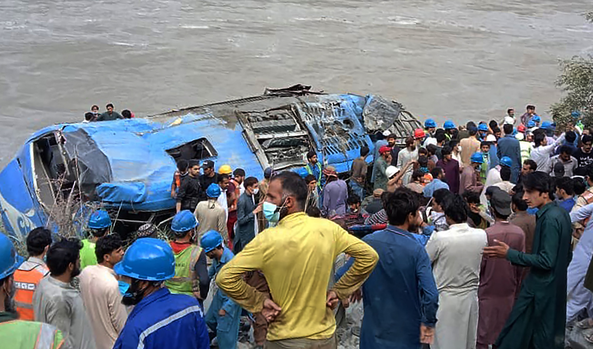 Rescue workers and onlookers gather around a wreck after a bus plunged into a ravine following a bomb explosion in Kohistan district of Khyber Pakhtunkhwa province on July 14, 2021. (AFP/File)