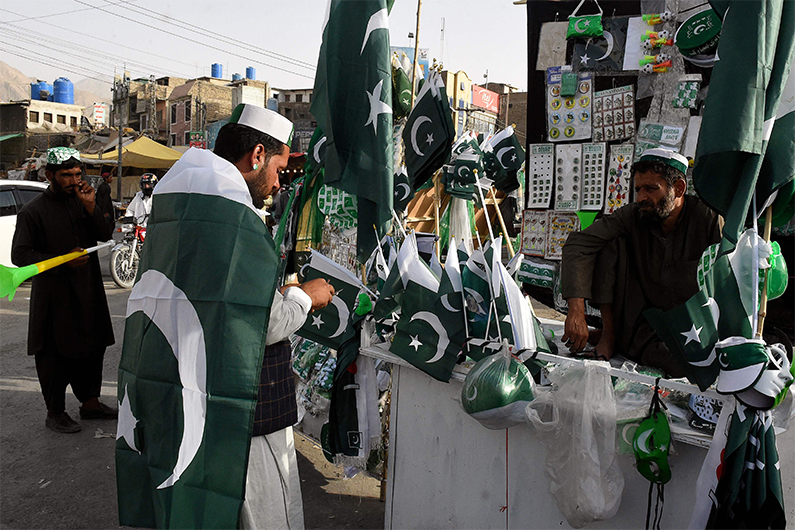 A man buys Pakistan's national flags at a roadside stall in Quetta on August 7, 2021. (AFP)