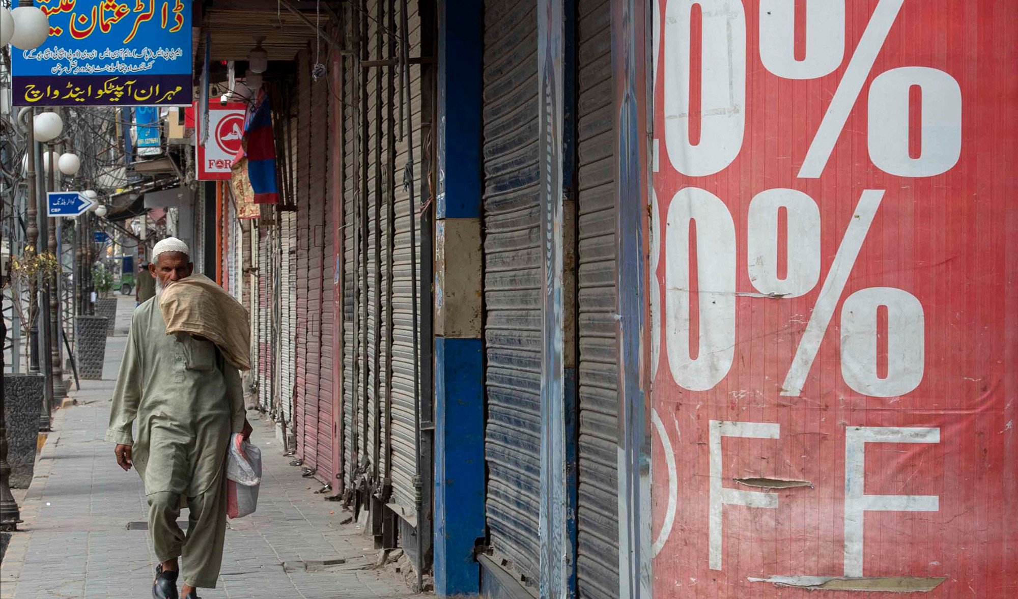 A man walks past shuttered shops in a commercial market area during lockdown, following new restrictions imposed as a preventive measure against the spread of the Covid-19 coronavirus, in Peshawar May 2, 2021. (AFP)