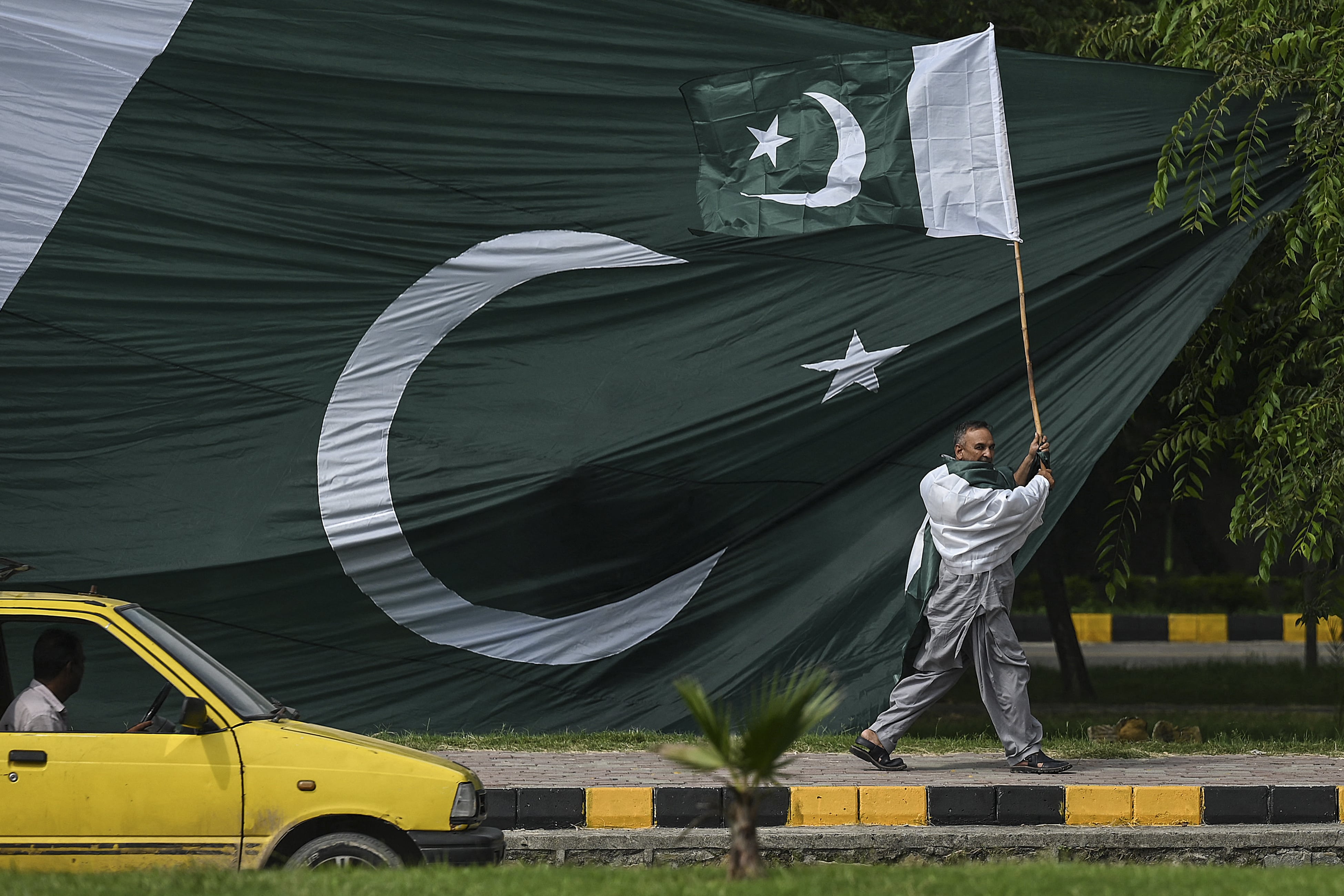 A man holds a national flag of Pakistan as he walks along a street in Islamabad on August 10, 2021, ahead of the country's 75th Independence Day, which marks the end of British colonial rule. (AFP)