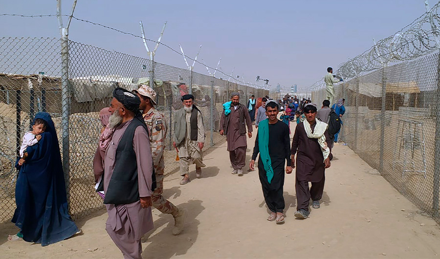 People walk through a security barrier while they enter Pakistan through a border crossing point, in Chaman, Pakistan, Monday, Aug. 16, 2021. (AP)