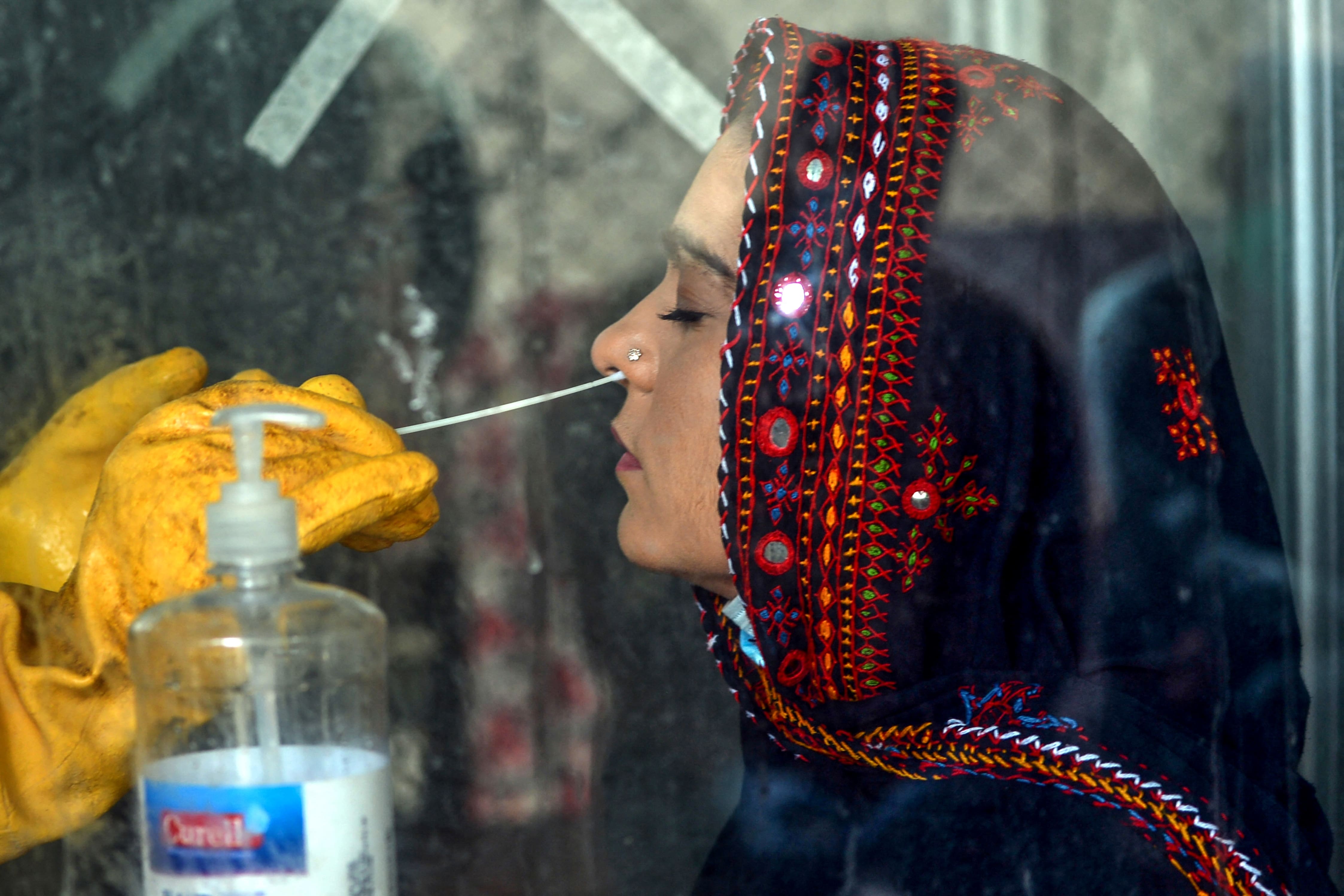 In this picture taken on July 23, 2020, a health worker wearing personal protective equipment (PPE) gear takes a swab sample from a woman to test for the COVID-19 coronavirus at a testing point in Karachi. (AFP/ File)