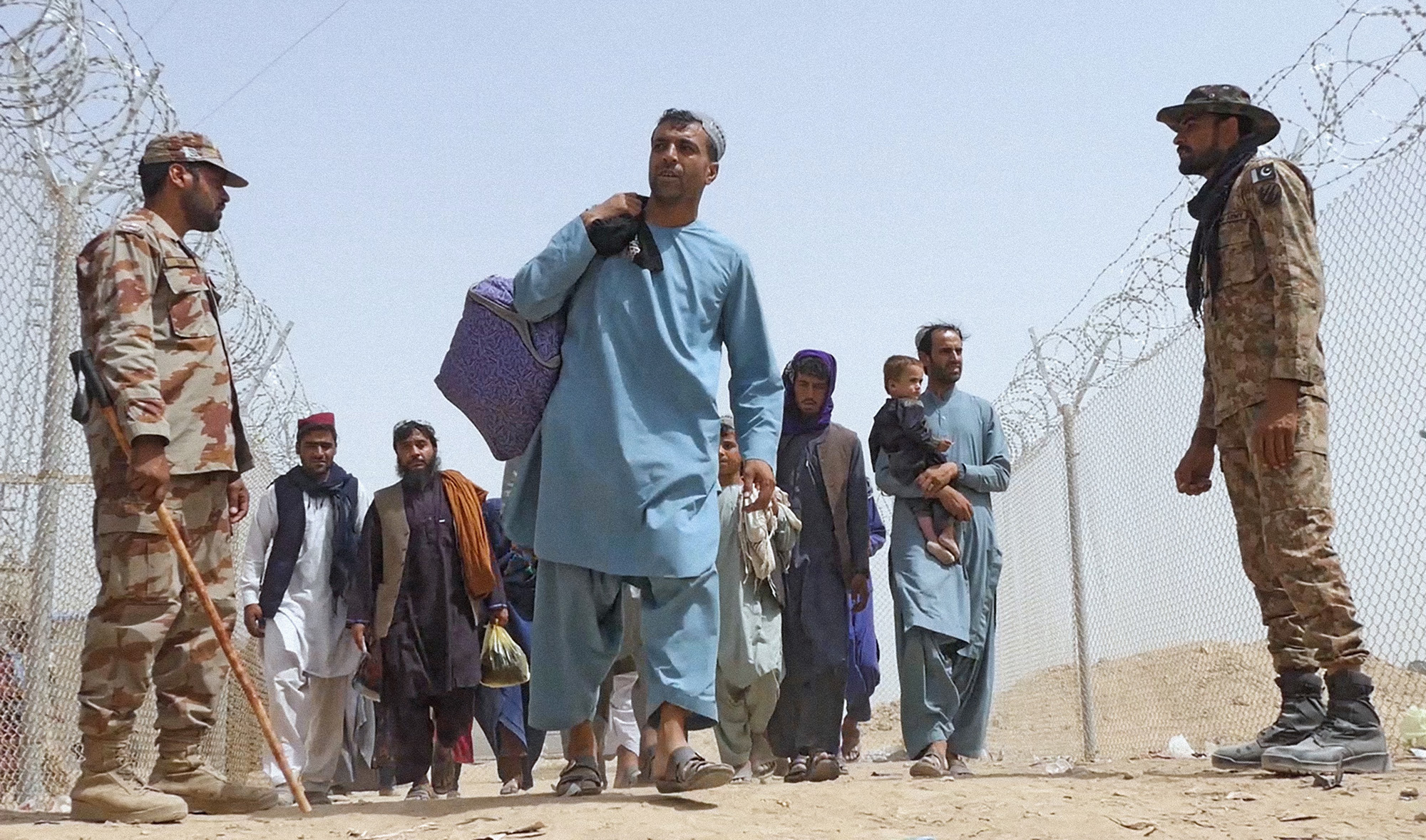 Afghans enter border town of Chaman walking past Pakistani soldiers manning the Pakistan-Afghanistan border crossing in Balochistan province - August 17, 2021. (AN photo)