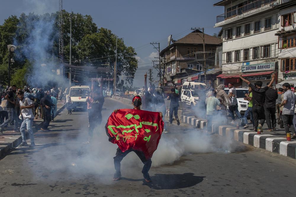 A Kashmiri Shiite Muslim holds religious banner as he stands amid tear gas smoke fired by Indian police man during a religious procession in central Srinagar, Indian controlled Kashmir, Tuesday, Aug. 17, 2021. (AP)