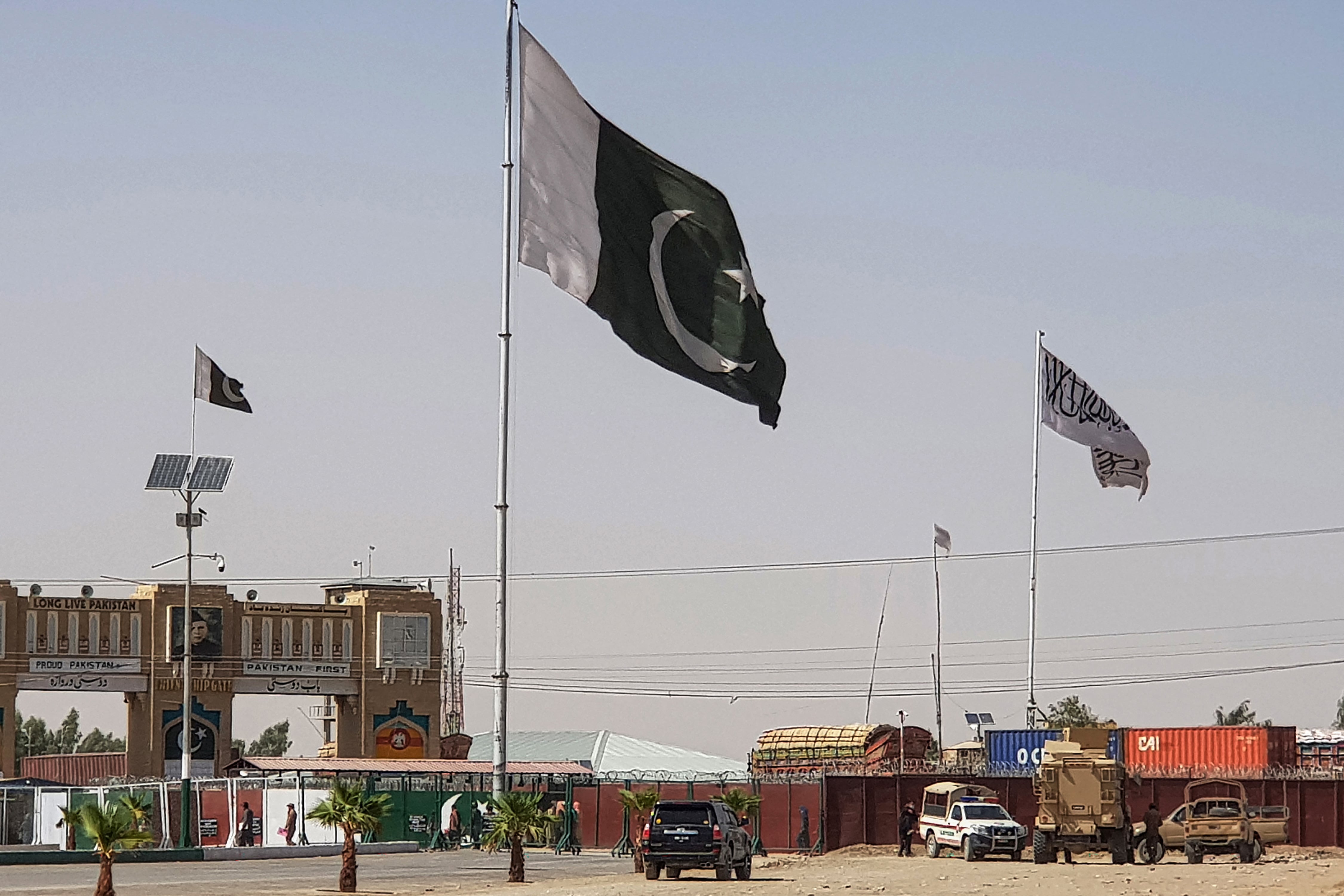 Pakistani flags (C) and Taliban flag (R) flutter on their respective border sides as seen from the Pakistan-Afghanistan border crossing point in Chaman on August 18, 2021. (AFP)
