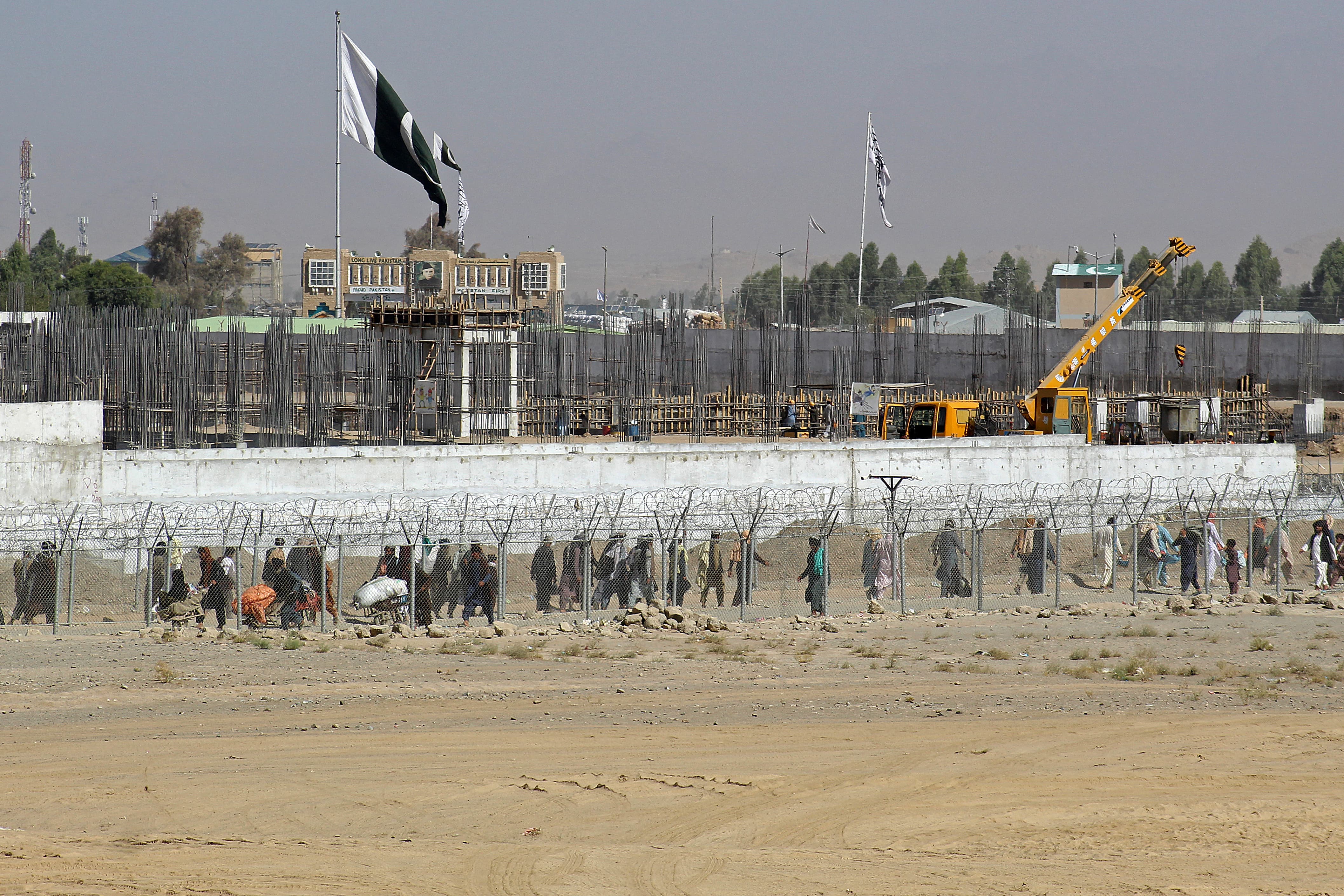 Afghan and Pakistani nationals walk through a security barrier to cross the border at the Pakistan-Afghanistan border crossing point in Chaman on August 22, 2021, following the Taliban stunning takeover of Afghanistan. (AFP)