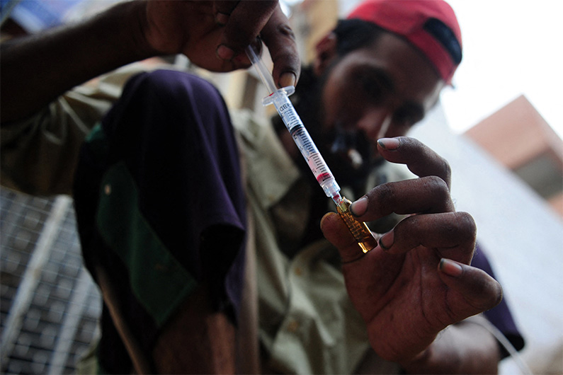 A Pakistani drug user prepares a syringe of a heroin along a street in Karachi on June 25, 2012. (AFP/ File)