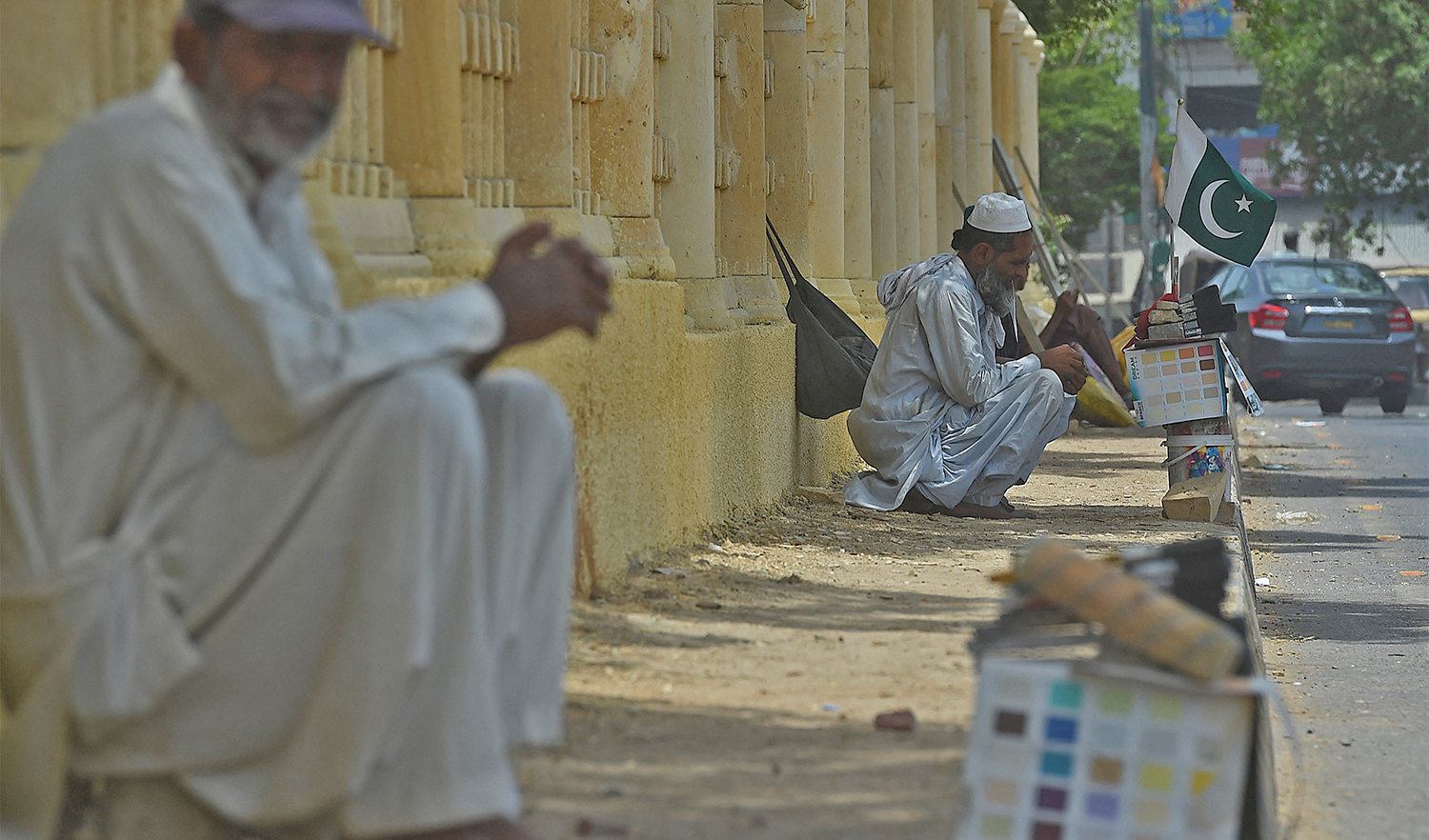Daily wage labourers sit along the roadside as they wait to be hired for work in Karachi, Pakistan, on June 11, 2021. (AFP/File)