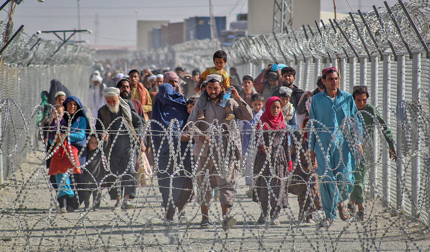 Afghans walk along fences as they arrive in Pakistan through the Pakistan-Afghanistan border crossing point in Chaman on August 24, 2021. (AFP/File)