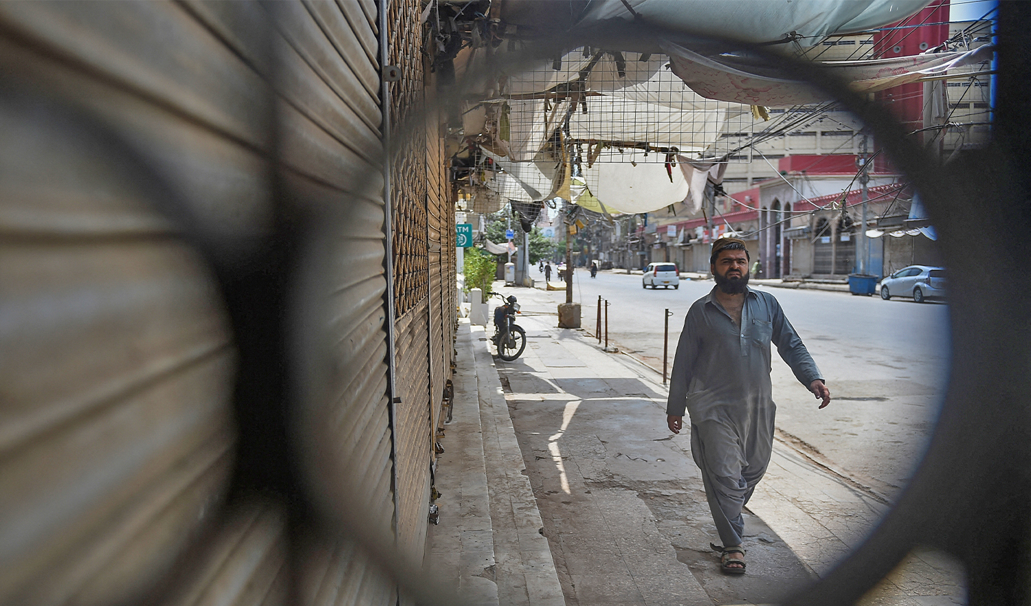 A man walks along a road next to closed shops at a commercial area as a partial lockdown is in effect to curb the spread of the Covid-19 in Karachi, Pakistan, on August 8, 2021. (AFP/File)