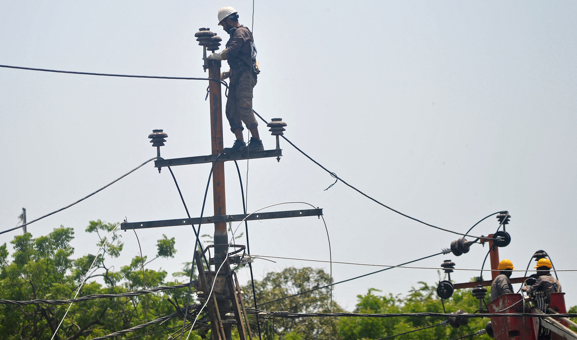 Men work on electric pylons along the roadside in Karachi, Pakistan, on May 30, 2021. (AFP/File)