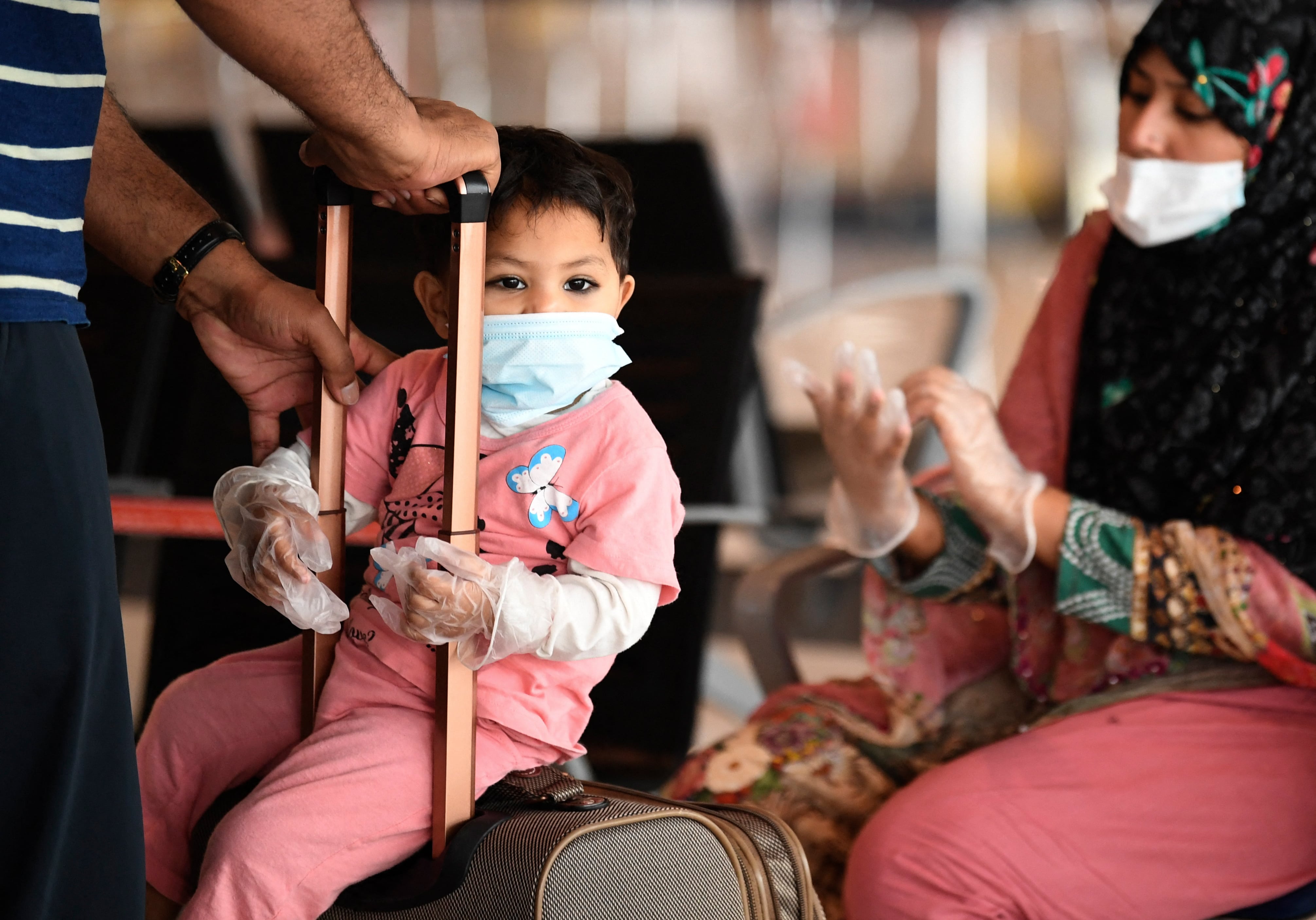 Members of a Pakistani family wait at the Dubai International Airport before leaving the Gulf Emirate on a flight back to their country, on May 7, 2020, amid the novel coronavirus pandemic crisis. (AFP)