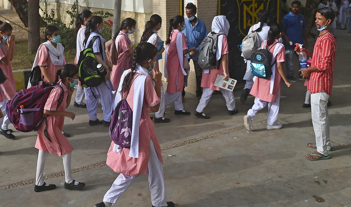A staff member helps the school children sanitize their hands before entering the premises of a school in Karachi on June 21, 2021. (AFP/File)
