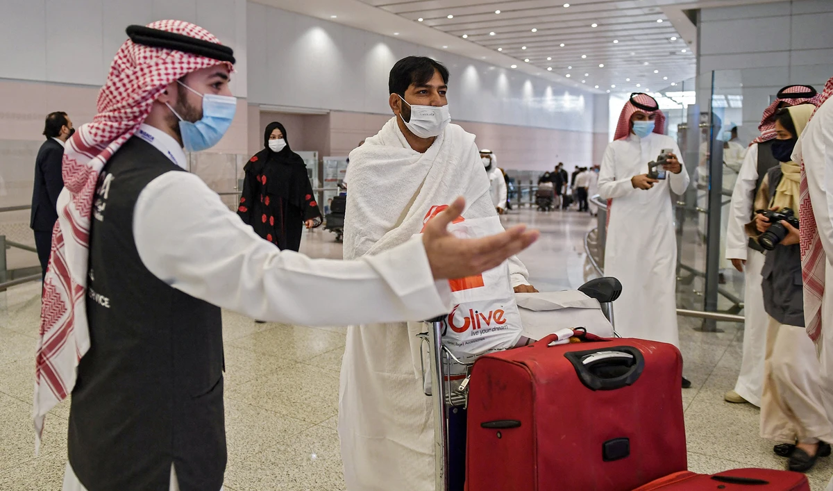 A mask-clad Pakistani traveller arriving to Saudi Arabia to perform the year-round Umrah pilgrimage, is welcomed at King Abdulaziz International Airport in Jeddah on November 30, 2020 (AFP/File)
