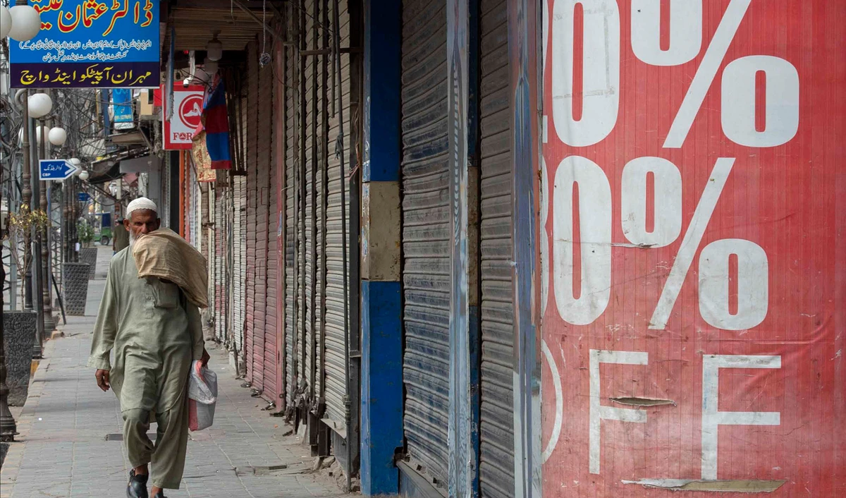 A man walks past shuttered shops in a commercial market area during lockdown, following new restrictions imposed as a preventive measure against the spread of the Covid-19 coronavirus, in Peshawar May 2, 2021. (AFP)