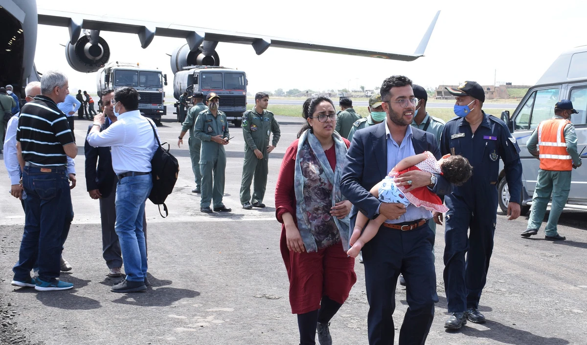 This photograph provided by Gujarat State Information Office shows an Indian embassy staff member with his family arrives at Air force base, in Jamnagar, India, Tuesday, August 17, 2021. (Gujarat State Information Office via AP)
