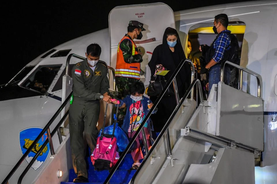 An Indonesian Airforce personnel helps a girl down the stairs of the aircraft as Indonesian citizens who were evacuated from Kabul, Afghanistan, arrive at Halim Perdanakusuma airbase in Jakarta, Indonesia, August 21, 2021. (REUTERS)