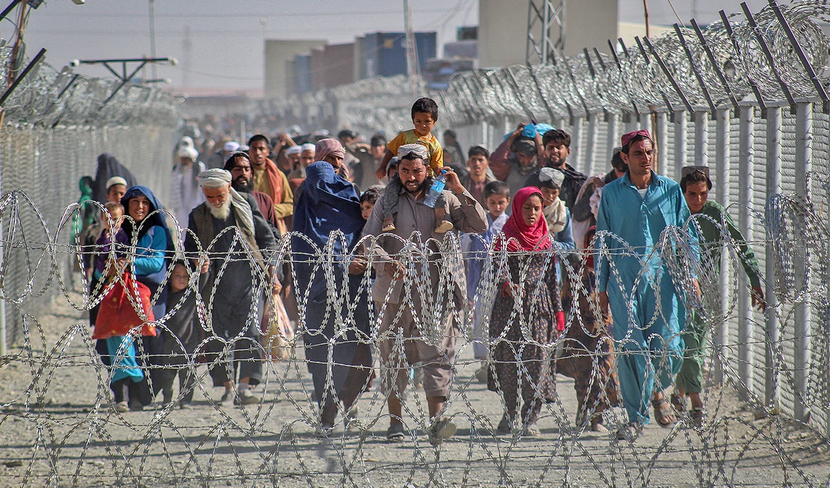 Afghans walk along fences as they arrive in Pakistan through the Pakistan-Afghanistan border crossing point in Chaman on August 24, 2021. (AFP/File)