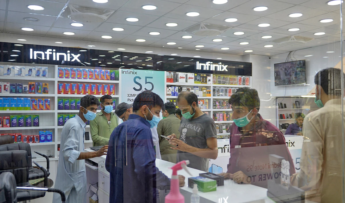 People wearing facemask buy mobile phones at a shop in a market in Rawalpindi, Pakistan, on June 1, 2020. (AFP/File)