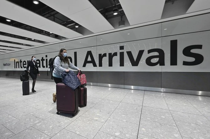Passengers arrive with lugagge at the Terminal 5 international arrivals hall at London Heathrow Airport in west London on February 14, 2021. (AFP)