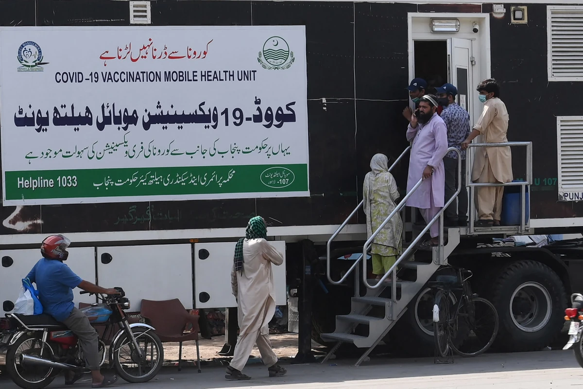 People wait for their turn to get a dose of a vaccine against the Covid-19 coronavirus outside a mobile vaccination health unit in Lahore on July 7, 2021. (AFP)