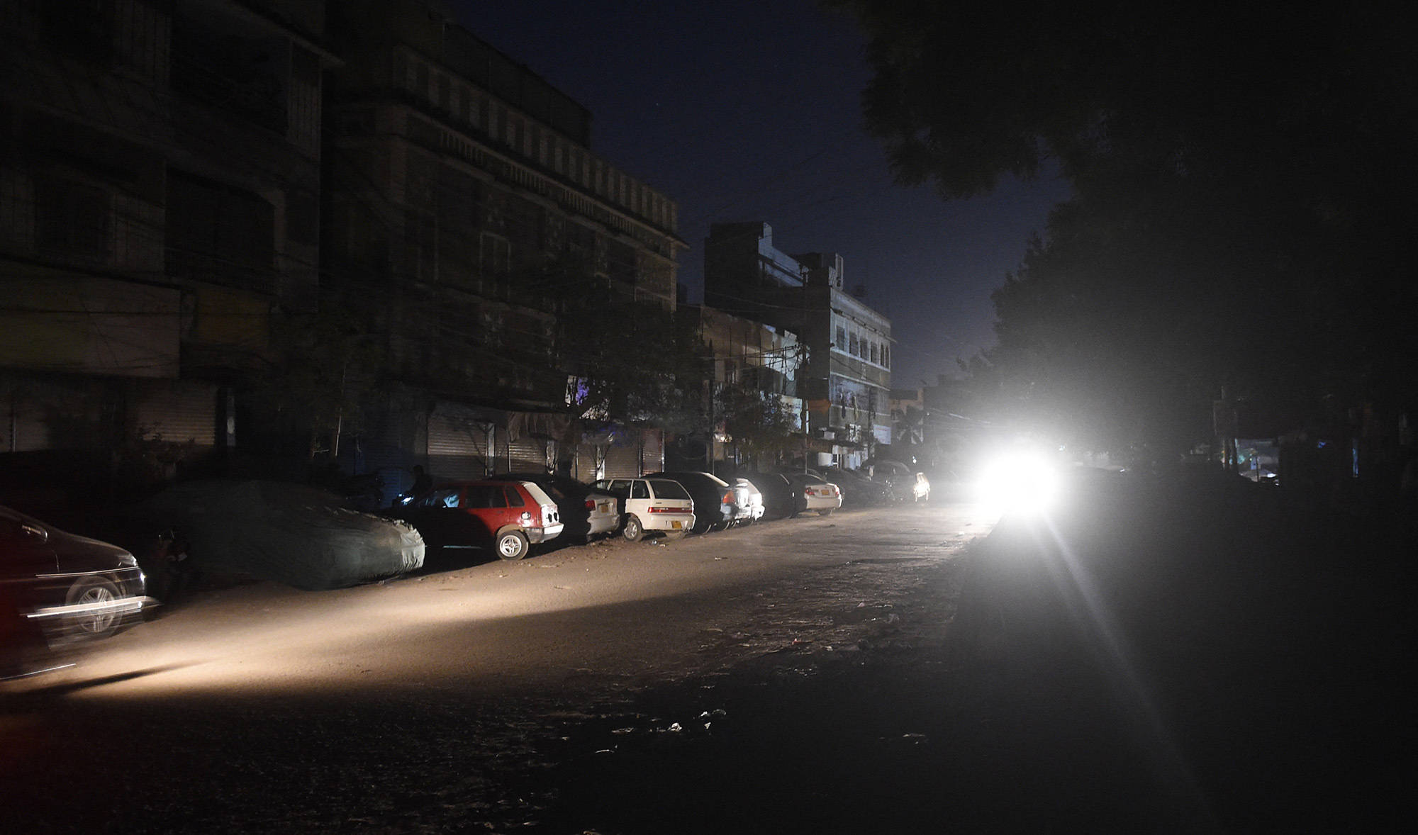 Motorists drive through a residential area during a power blackout in Pakistan's port city of Karachi early on January 10, 2021. (AFP/File)
