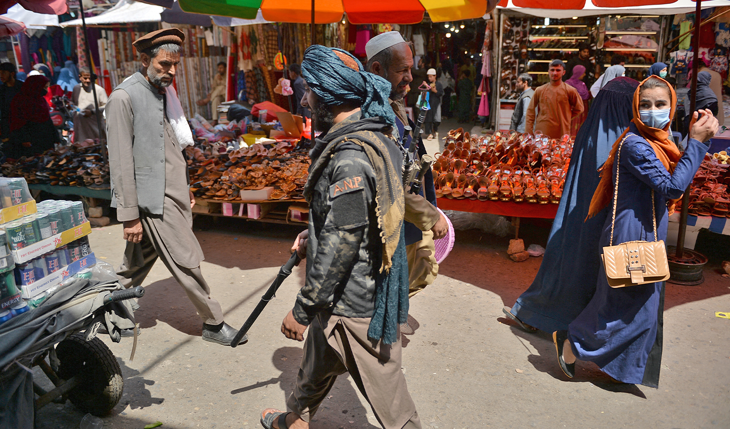 A Taliban fighter (right) walks past shoppers along Mandawi market in Kabul, Pakistan, on September 1, 2021. (AFP)