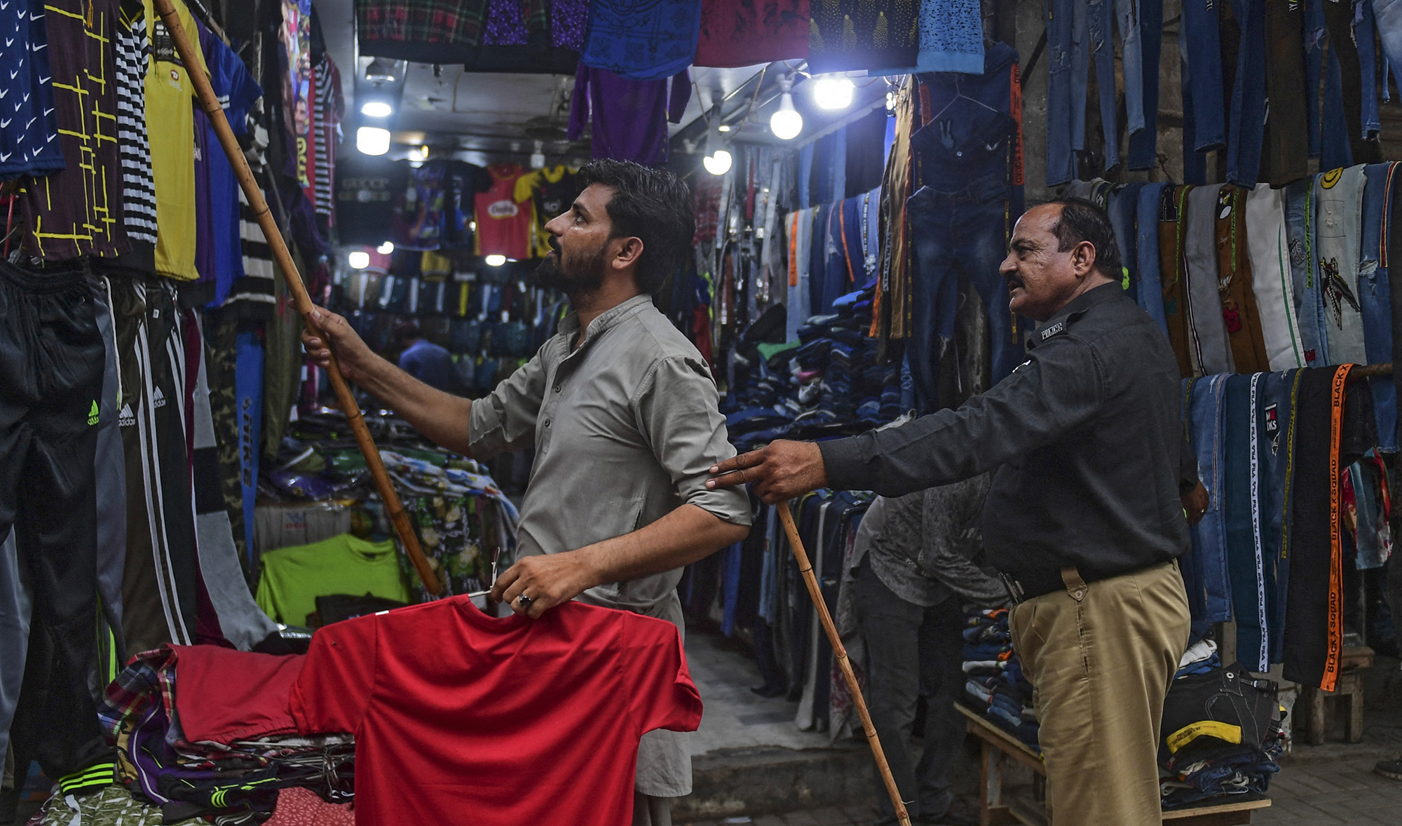 A policeman orders shopkeepers to close their shops after authorities imposed evening lockdowns amidst rising Covid-19 coronavirus cases in Karachi on July 26, 2021. (AFP/File)