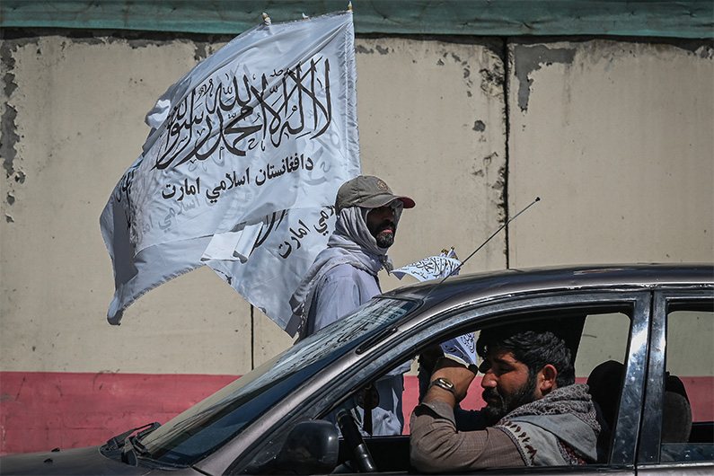 A mobile hawker carries Taliban flags as commuters make their way along a road in Kabul on September 5, 2021. (AFP)