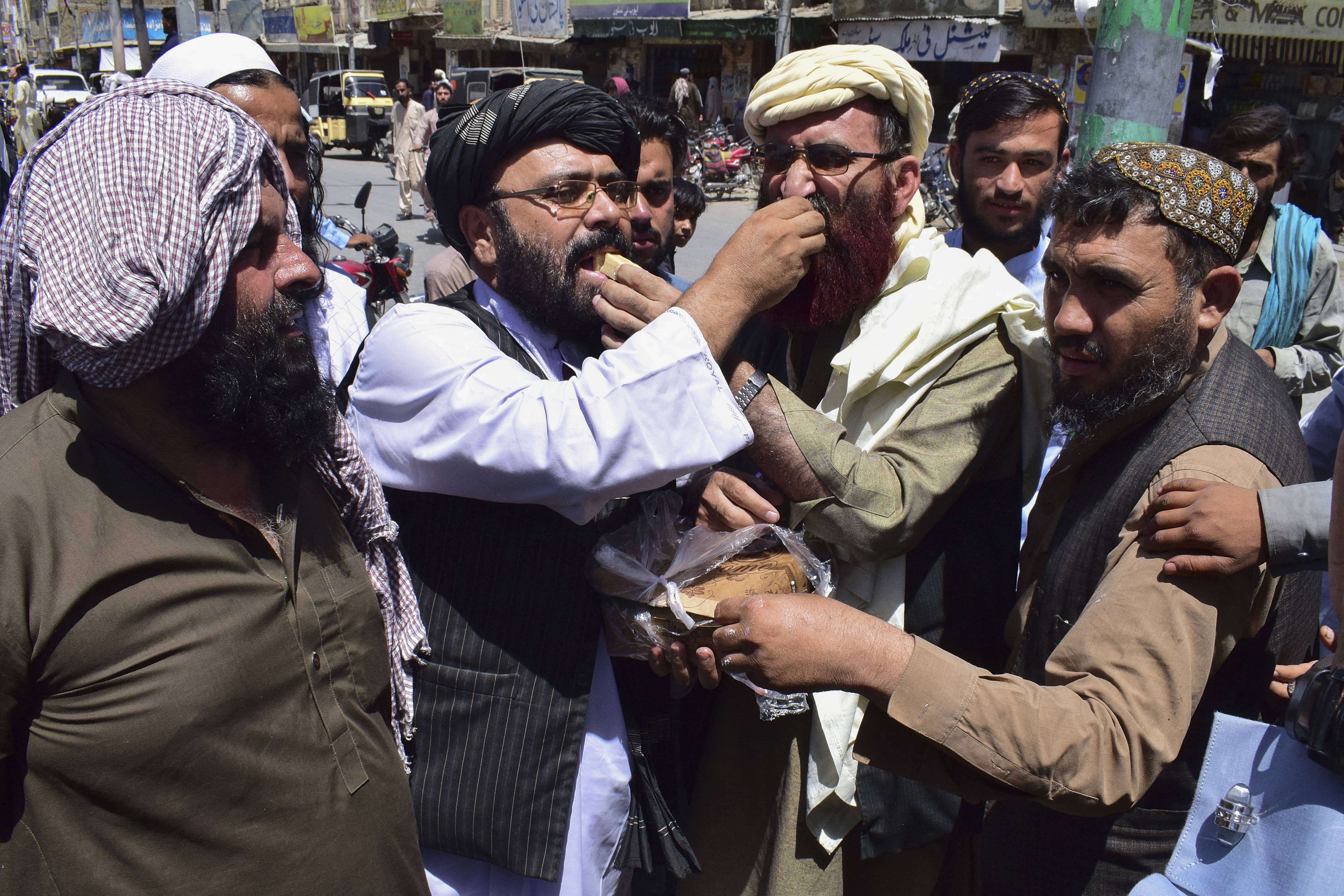 Supporters of the hardline pro-Taliban party Jamiat Ulema-i-Islam-Nazaryati (JUI-N) eat sweets as they celebrate the capture of cities in Afghanistan by the Taliban, in Quetta on August 13, 2021. (AFP)
