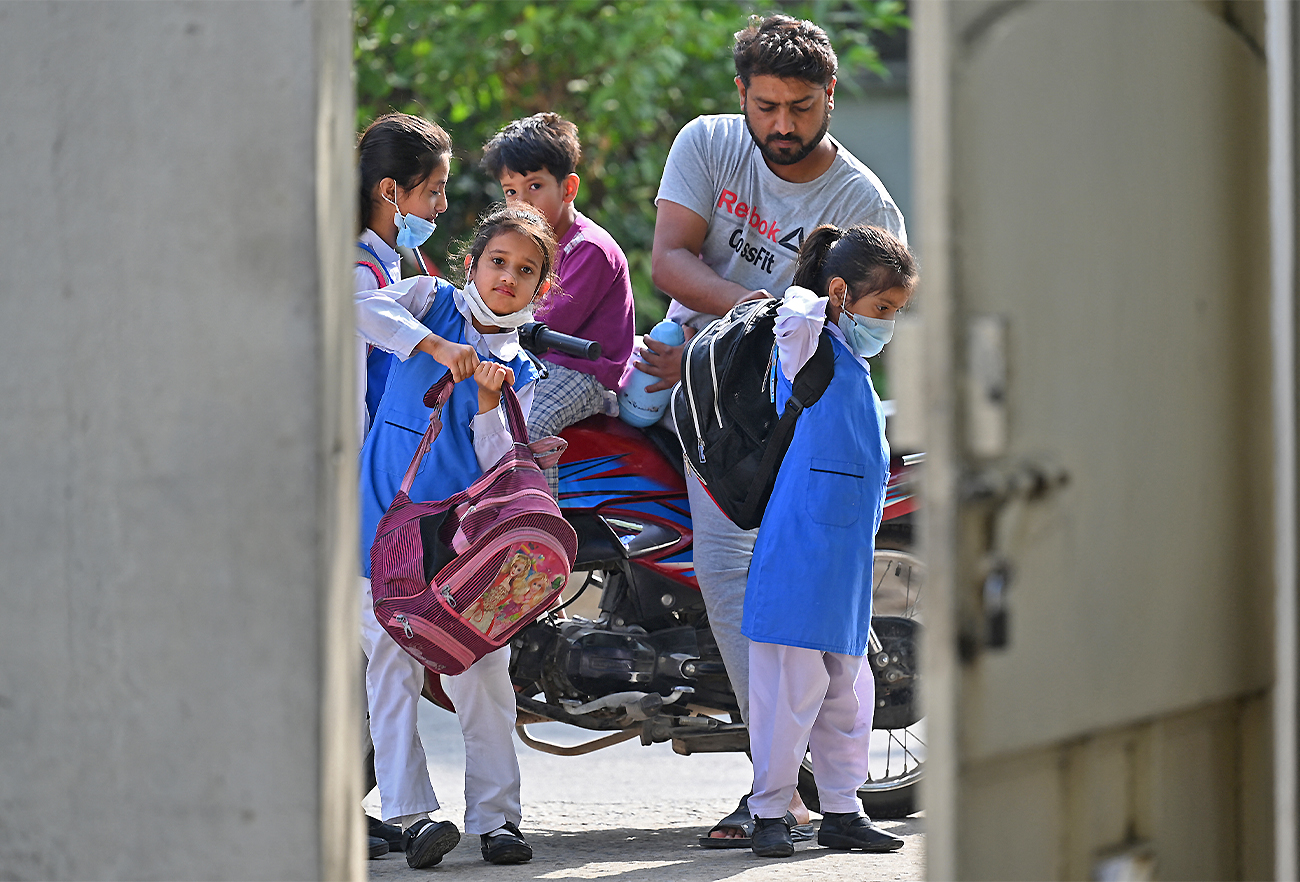A man drops children to a school in Islamabad, Pakistan, on June 7, 2021, as the government reopened educational institutes. (AFP)