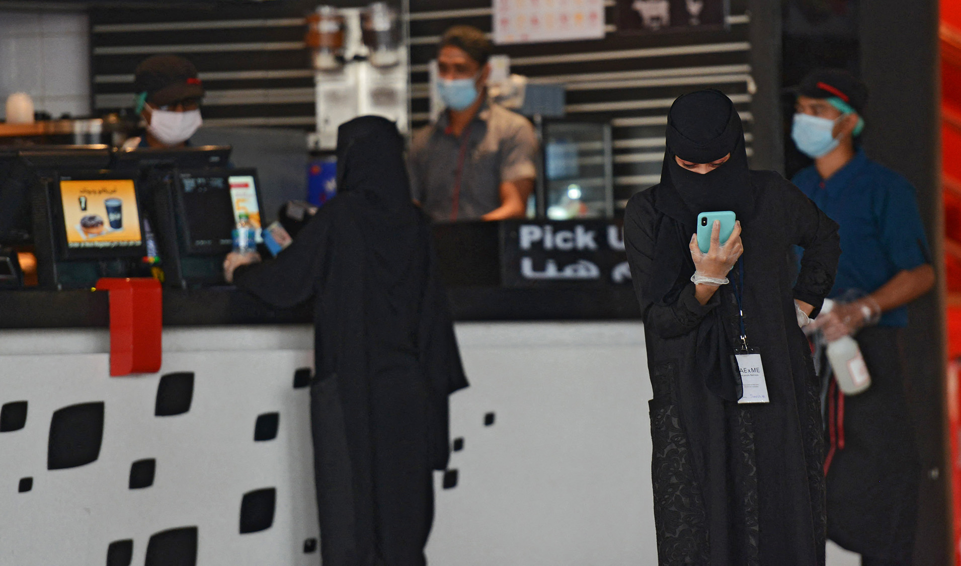 A woman checks her mobile as another orders food from a restaurant in a mall in Riyadh, Saudi Arabia on June 4, 2020. (AFP/File)