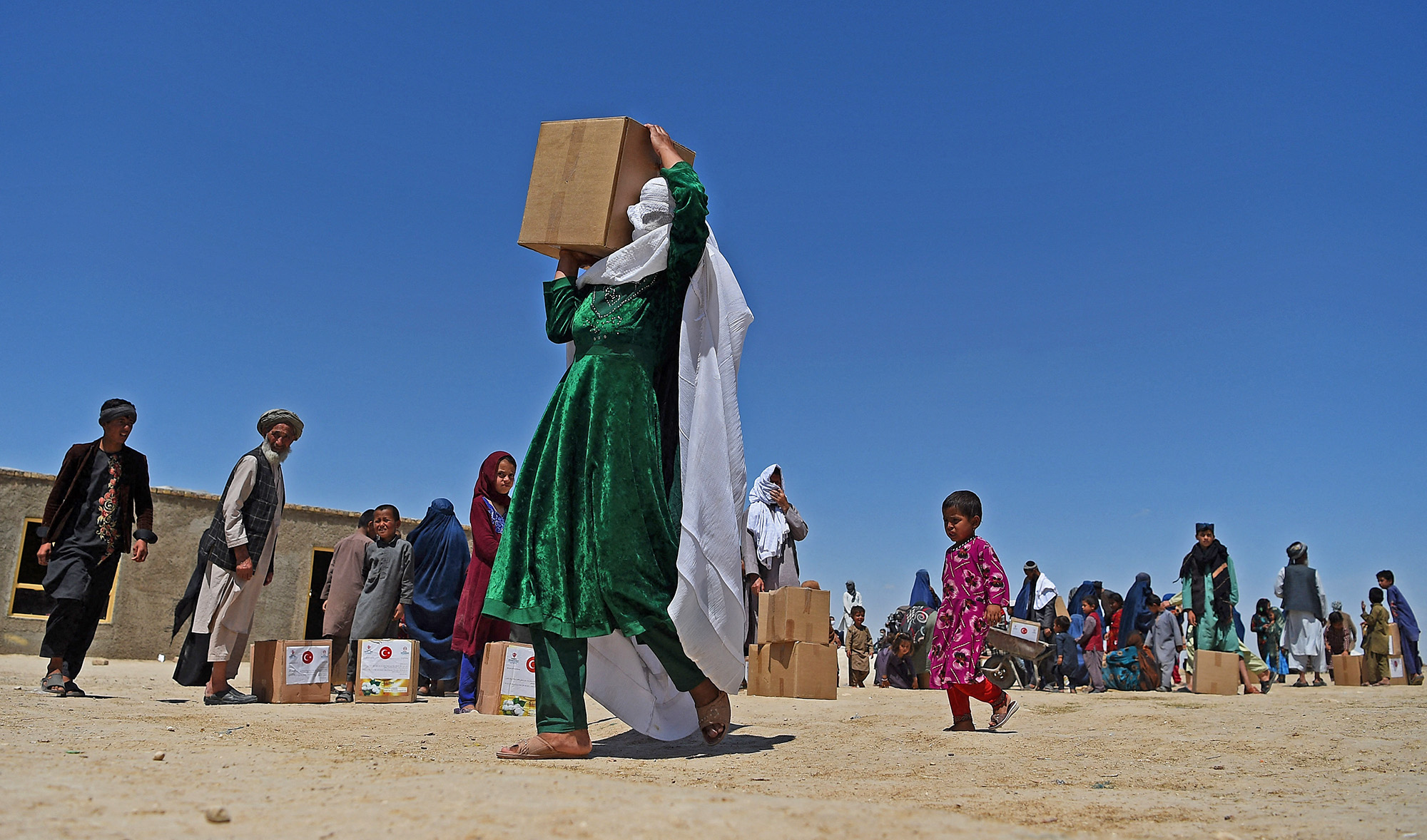 A woman carries free aid over her shoulders distributed during the Holy month of Ramadan in a refugee camp on the outskirts of Mazar-i-Sharif, Afghanistan, on May 3, 2020. (AFP/File)
