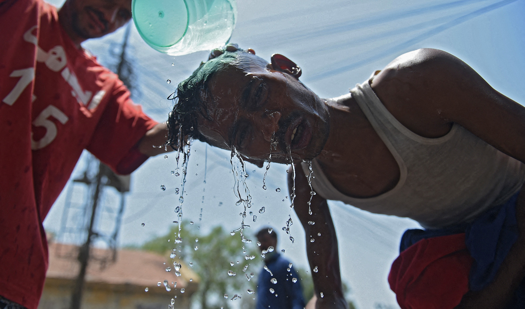 A volunteer from Edhi Foundation cools off a man with water along the roadside on a hot summer day in Karachi on May 17, 2021. (AFP/File)
