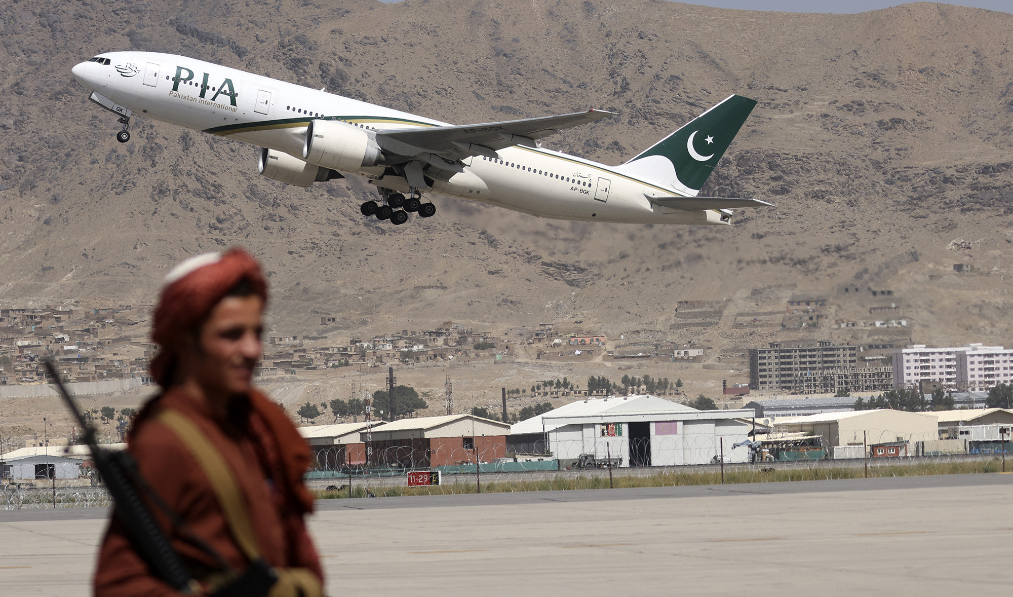 A Taliban fighter stands guard as a Pakistan International Airlines plane takes off at the airport in Kabul, Afghanistan, on September 13, 2021. (AFP/File)
