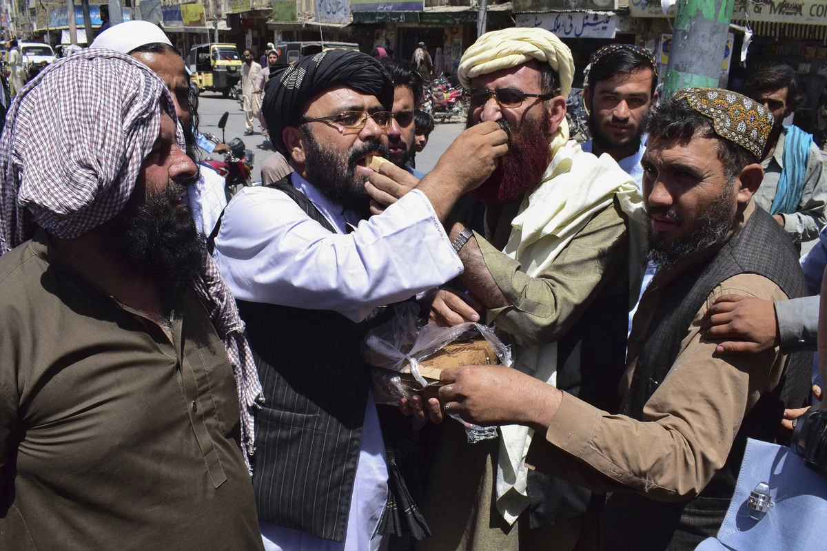 Supporters of the hardline pro-Taliban party Jamiat Ulema-i-Islam-Nazaryati (JUI-N) eat sweets as they celebrate the capture of cities in Afghanistan by the Taliban, in Quetta on August 13, 2021. (AFP)