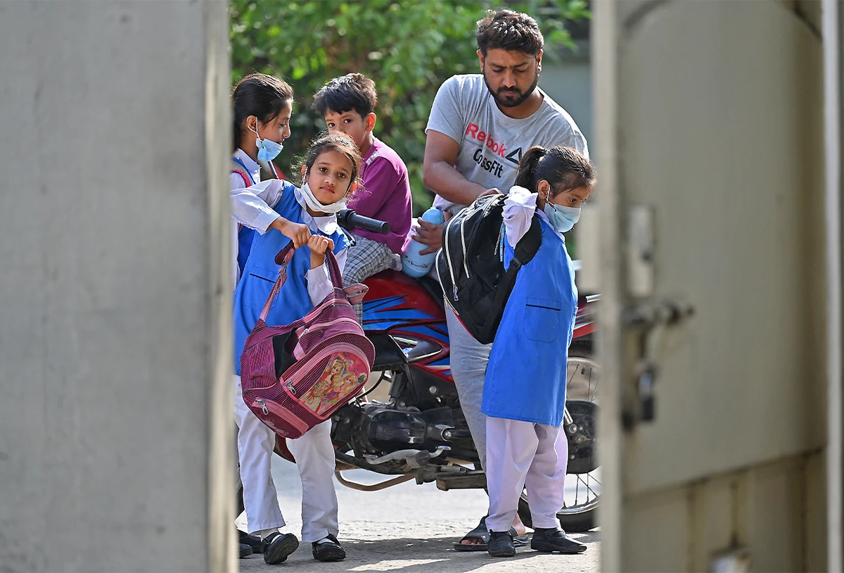 A man drops children to a school in Islamabad, Pakistan, on June 7, 2021, as the government reopened educational institutes. (AFP)