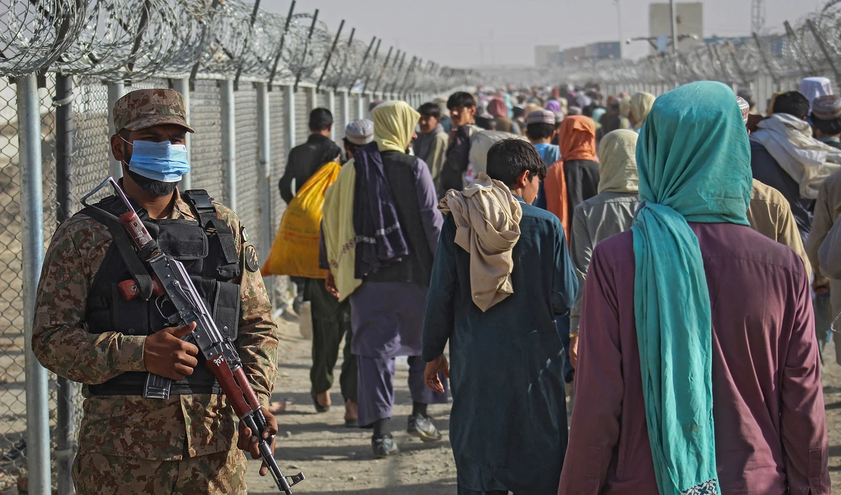 A Pakistani soldier stands guard as Afghans walk along fences after arriving in Pakistan through the Pakistan-Afghanistan border crossing point in Chaman on August 26, 2021. (AFP/File)
