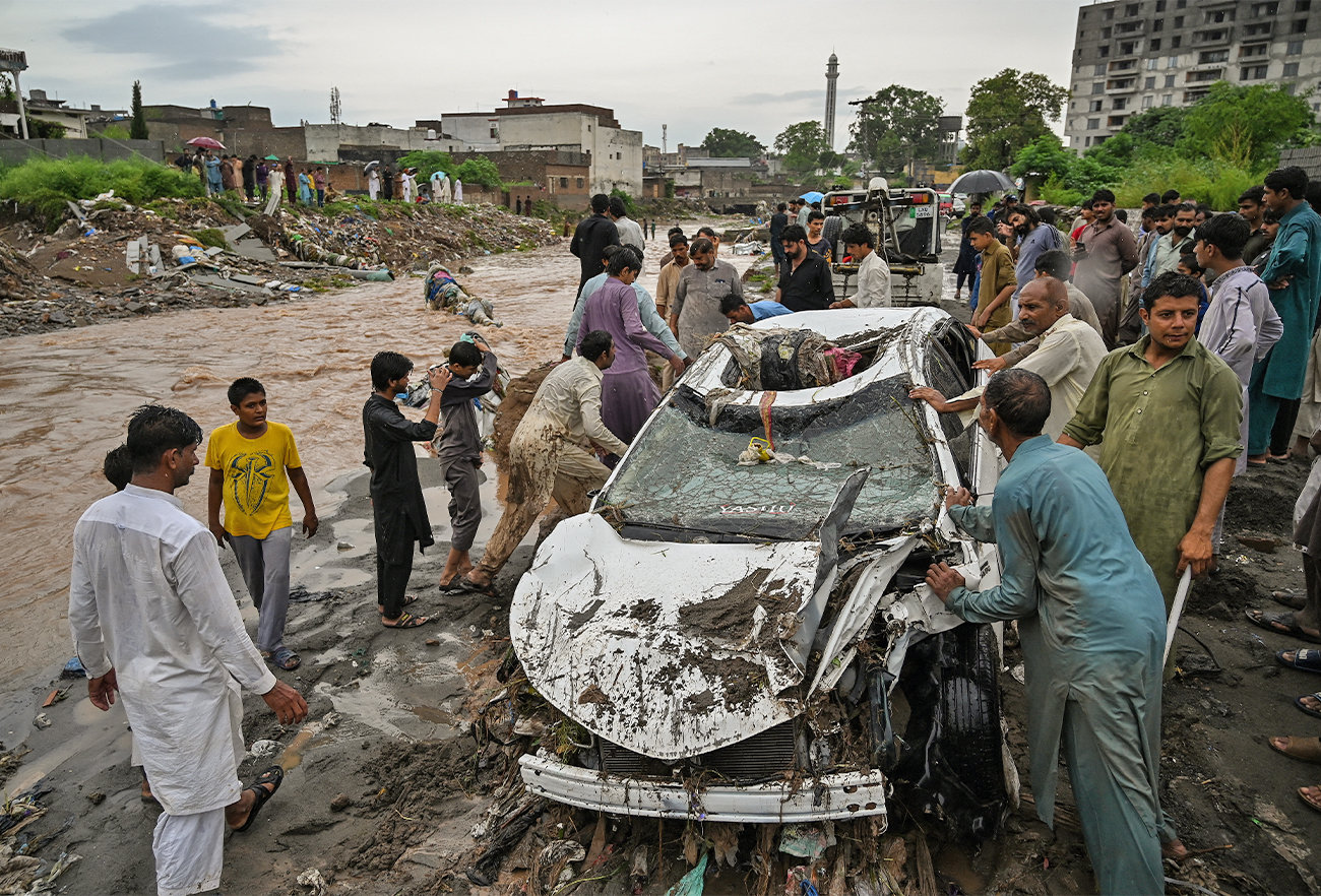 Residents try to move a damaged car stuck in the mud along a street flooded after heavy monsoon rains in Islamabad, Pakistan, on July 28, 2021. (AFP/File)