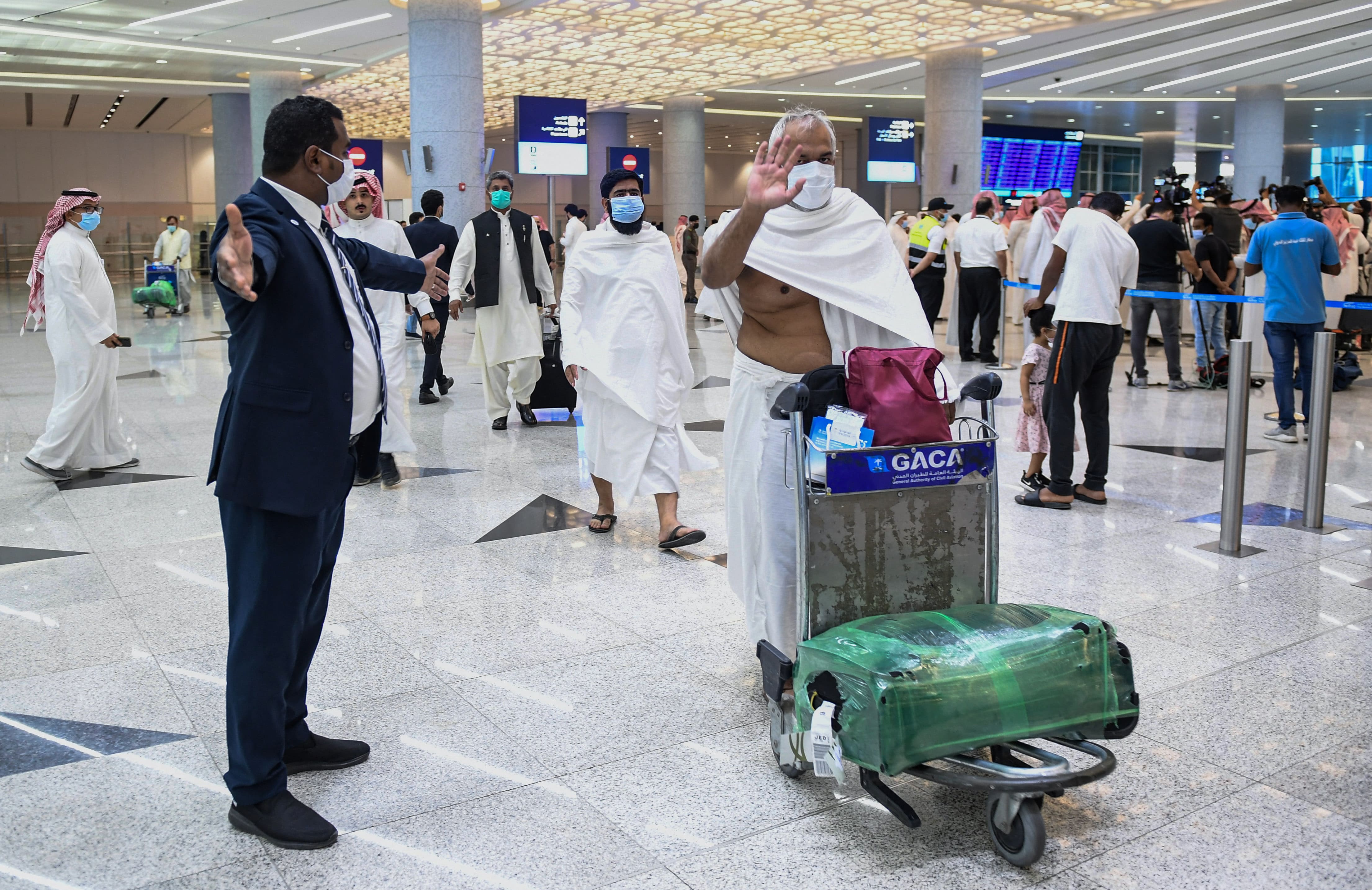 Mask-clad Pakistani travellers arriving to Saudi Arabia to perform the year-round Umrah pilgrimage, walk with their luggage at King Abdulaziz International Airport in the Red Sea coastal city of Jeddah on November 30, 2020. (AFP/ File)