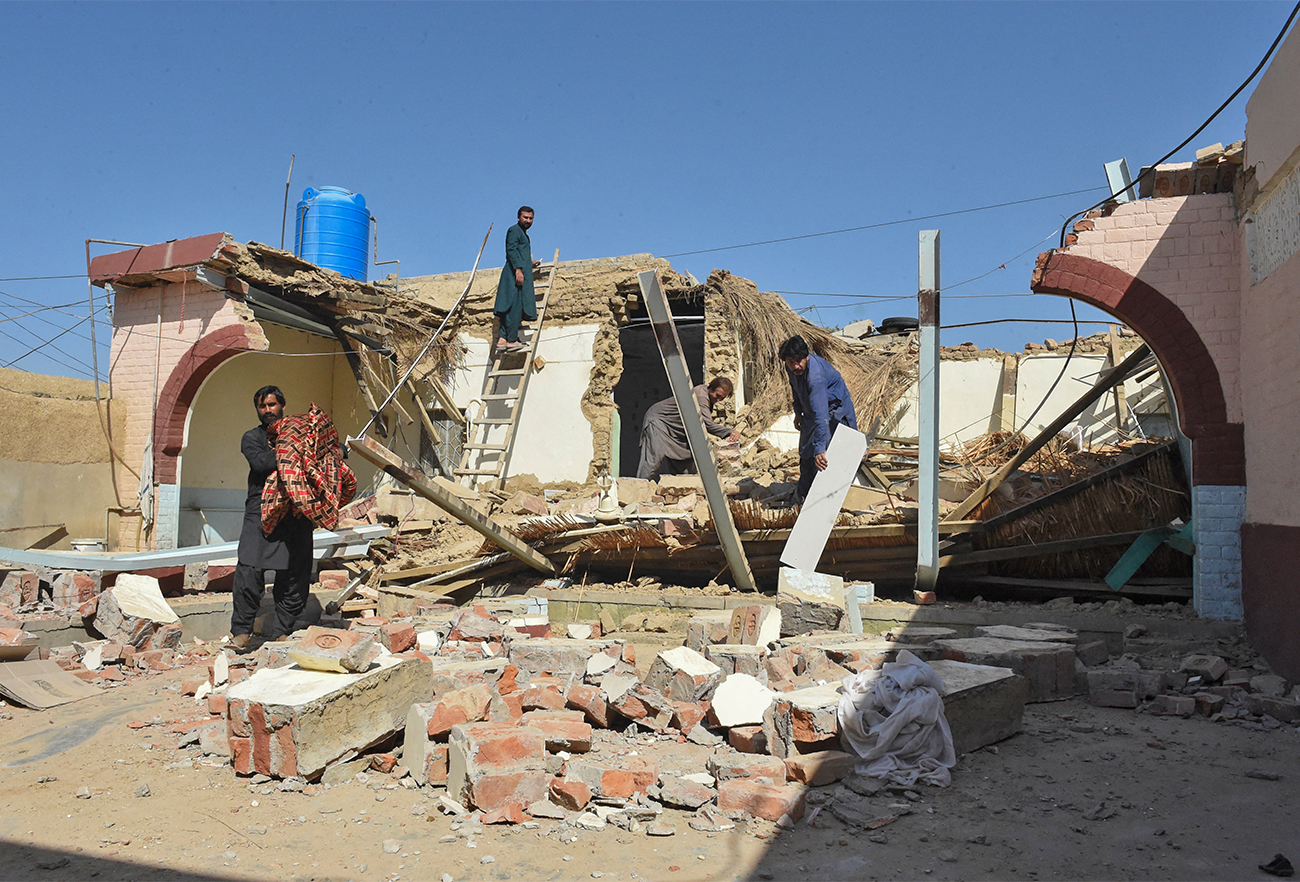 A resident shifts a fan from his collapsed house a day after an earthquake struck the remote mountainous district of Harnai in southwest Pakistan on October 8, 2021. (AFP)