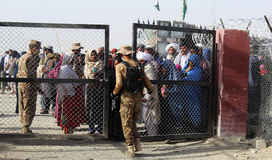 A Pakistani soldier holds a gate as Afghan and Pakistani people wait to enter Afghanistan through the Pakistan-Afghanistan border crossing point in Chaman on August 27, 2021. (AFP)